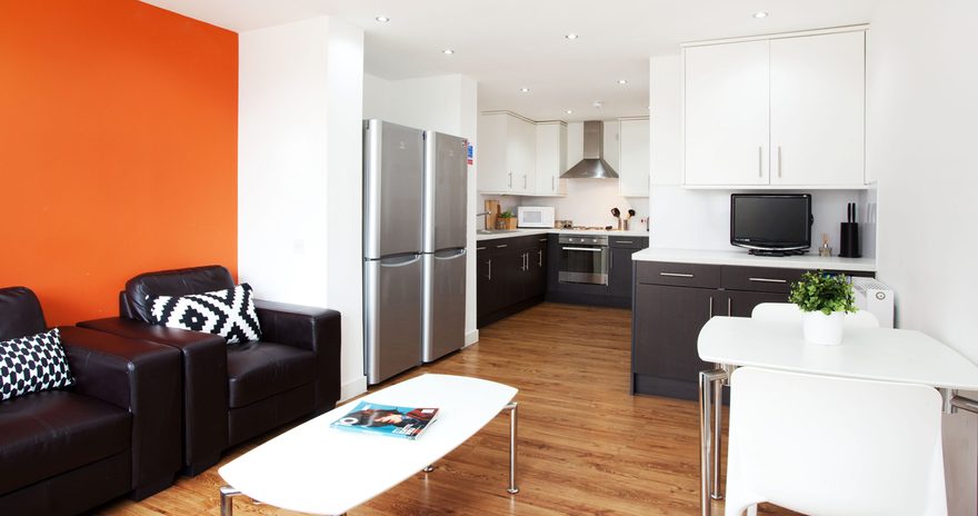 the shared kitchen containing two armchairs, fridge-freezer, oven, hob, cupboards, dining table in at tramworks in glasgow