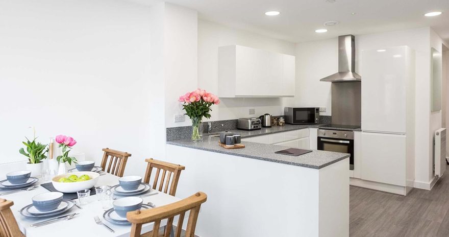 A shared kitchen with dining table, chairs, hob and sink at Chapter Lewisham