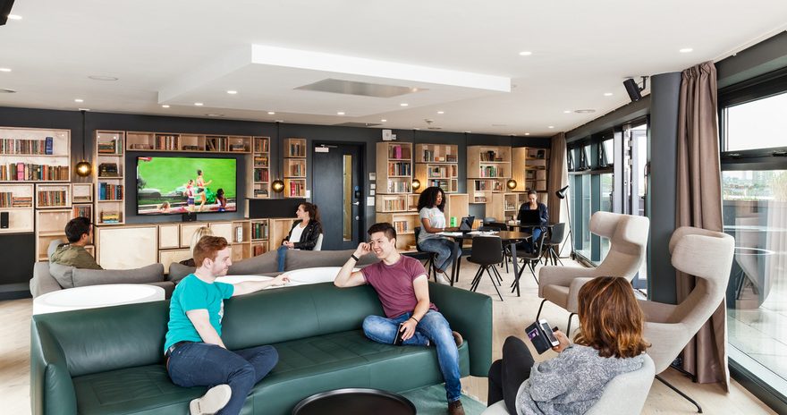 Social space with TV, sofas, book shelves, tables and chairs at Urbanest Hoxton in London