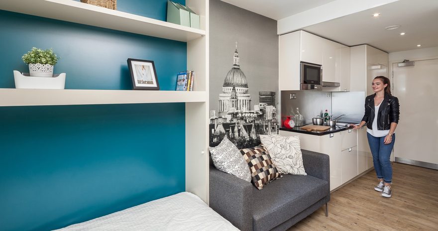 The studio flat with a bed, shelves, cupboards, a small sofa and a kitchenette at Urbanest Hoxton in London