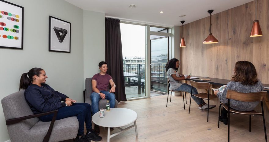 Four students in a social space with armchairs, study desk and access to a balcony at Urbanest Hoxton