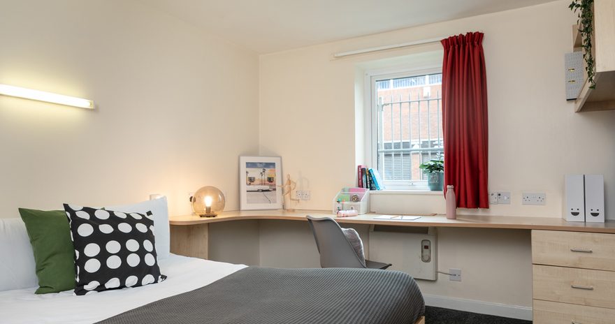 Premium ensuite featuring a small double bed, a study desk and a window in front of the desk