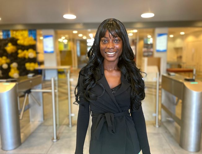 A student smiling at the entrance of the Kaplan Living Nottingham accommodation