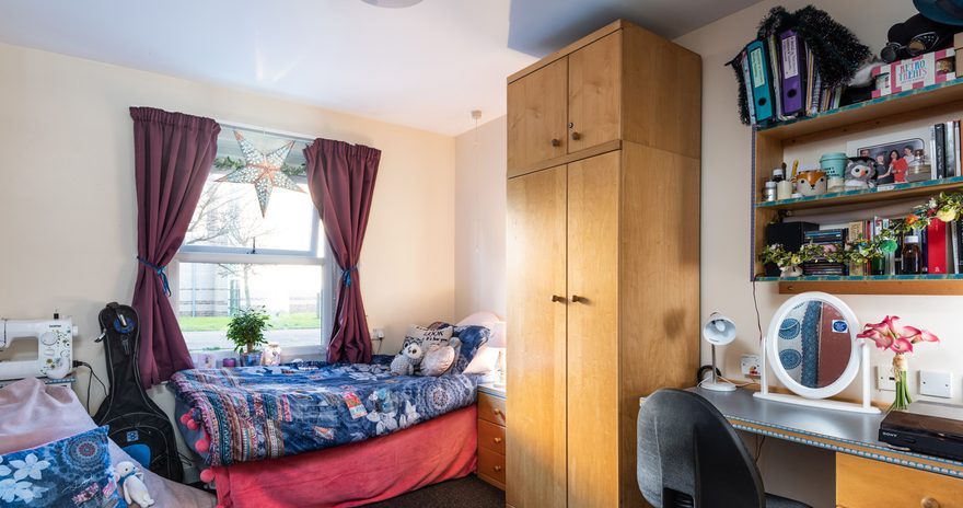 A standard ensuite with a bed, window, wardrobe and study desk