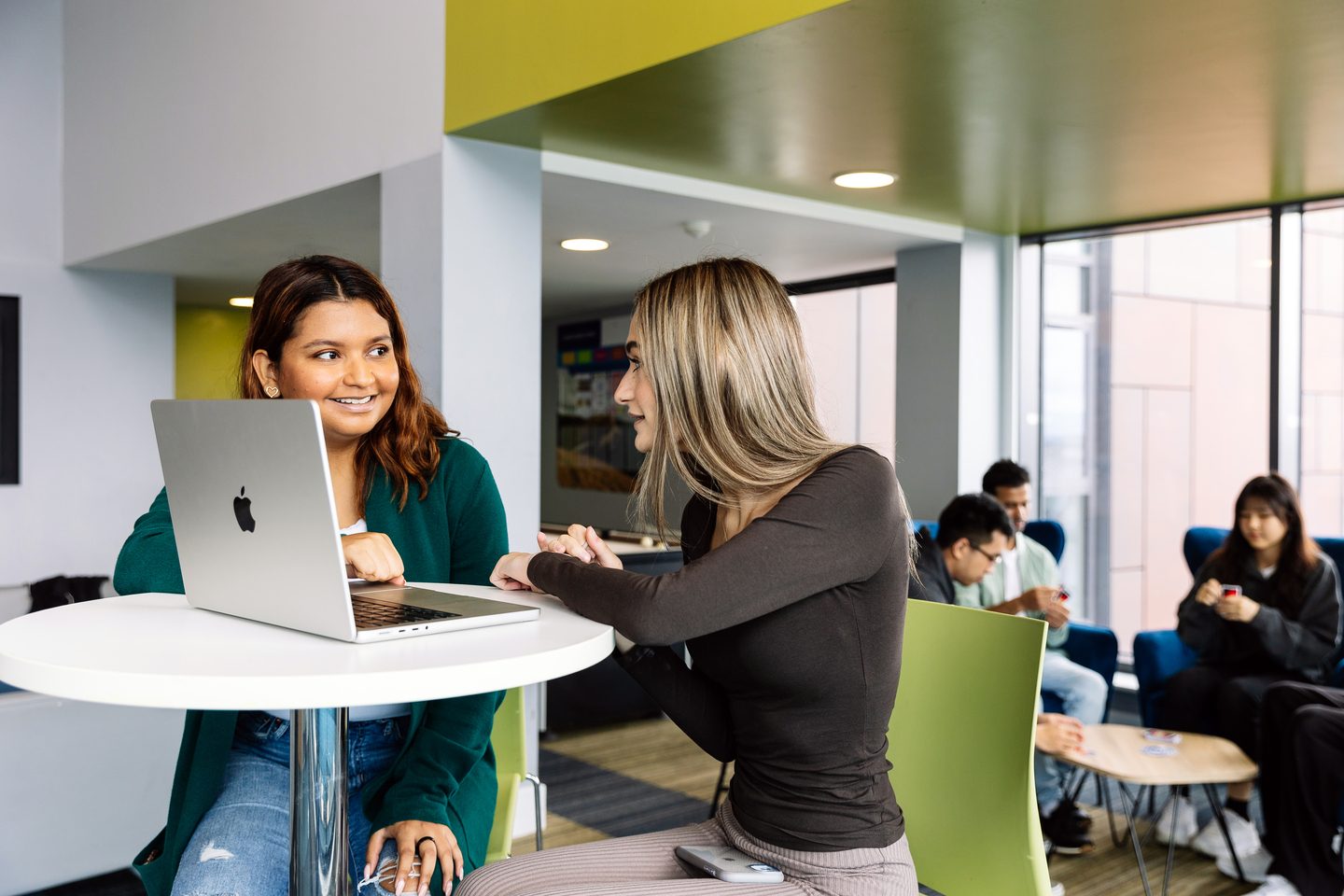Two students chatting and working in a common area